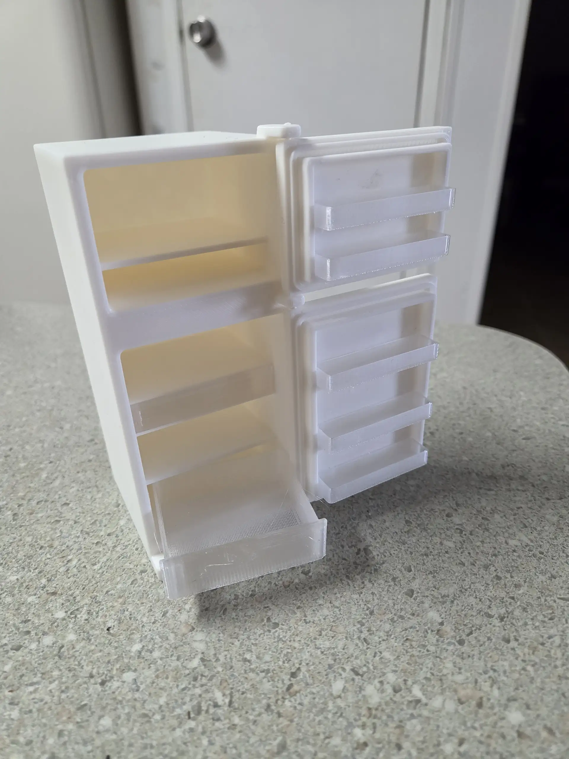 Separated 3D printed refrigerator parts with shelves drawers doors and handles