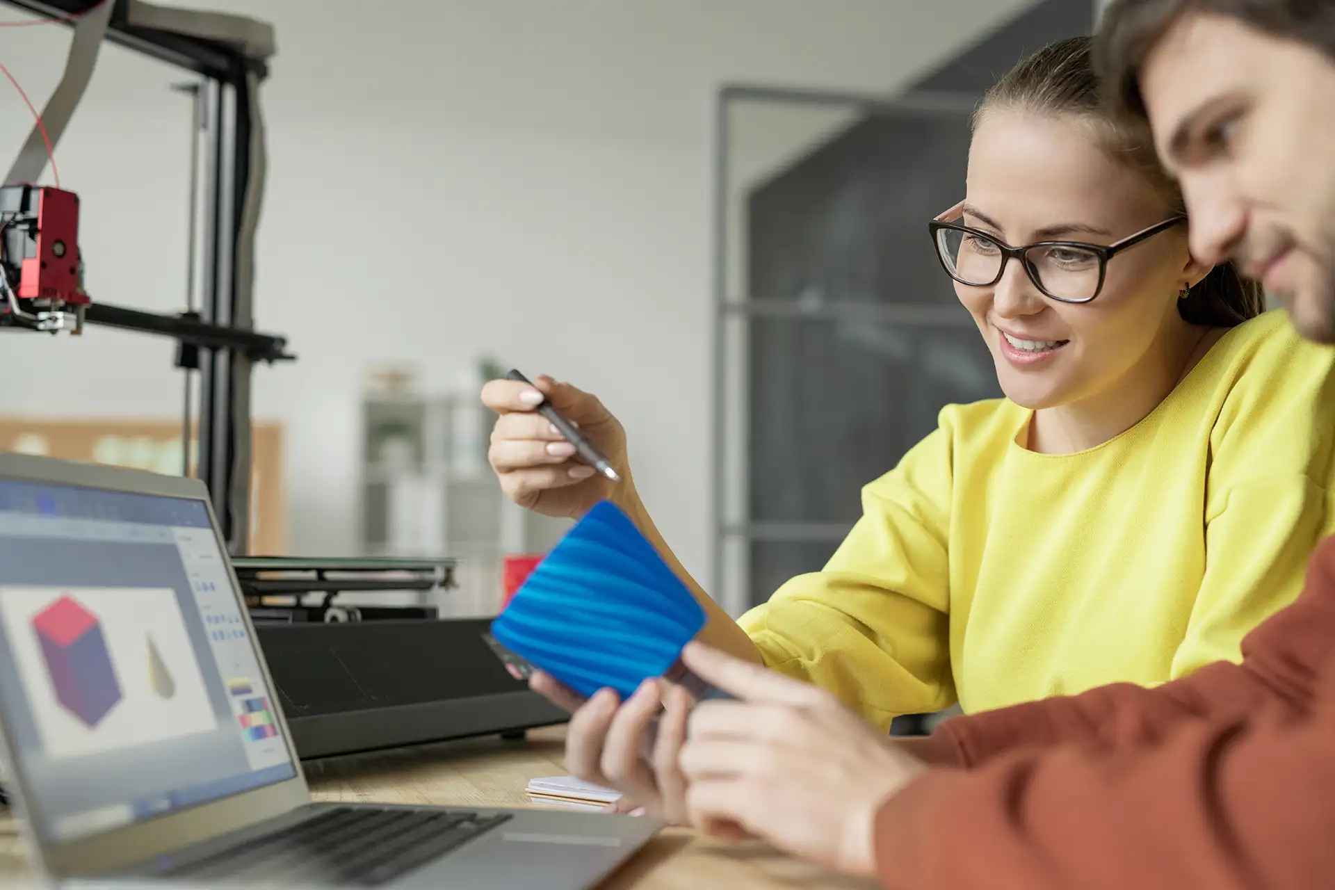 Woman and man working together on 3D printer design project at a modern workstation