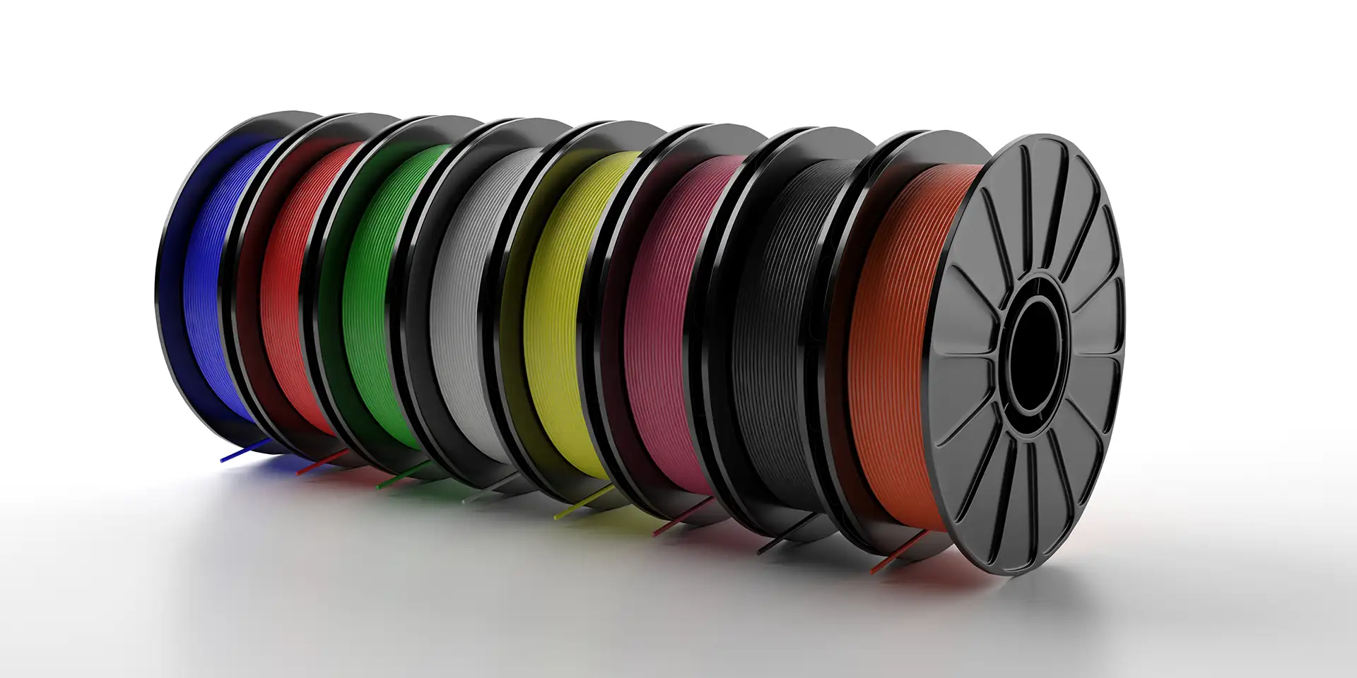 Colorful 3D printer filament spools on white surface showing PLA color range