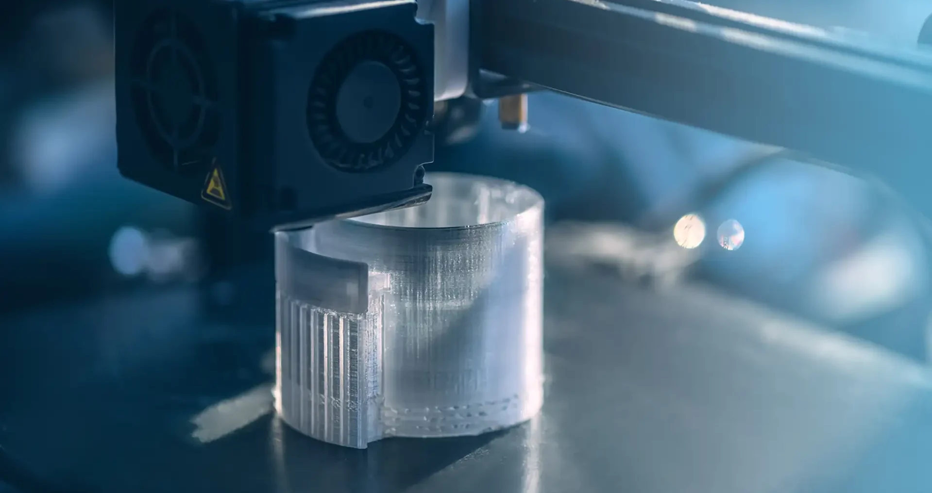 3D printer creating a round plastic object showing the FDM layer-by-layer printing process
