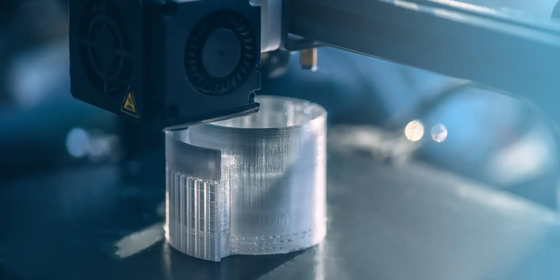3D printer creating a round plastic object showing the FDM layer-by-layer printing process