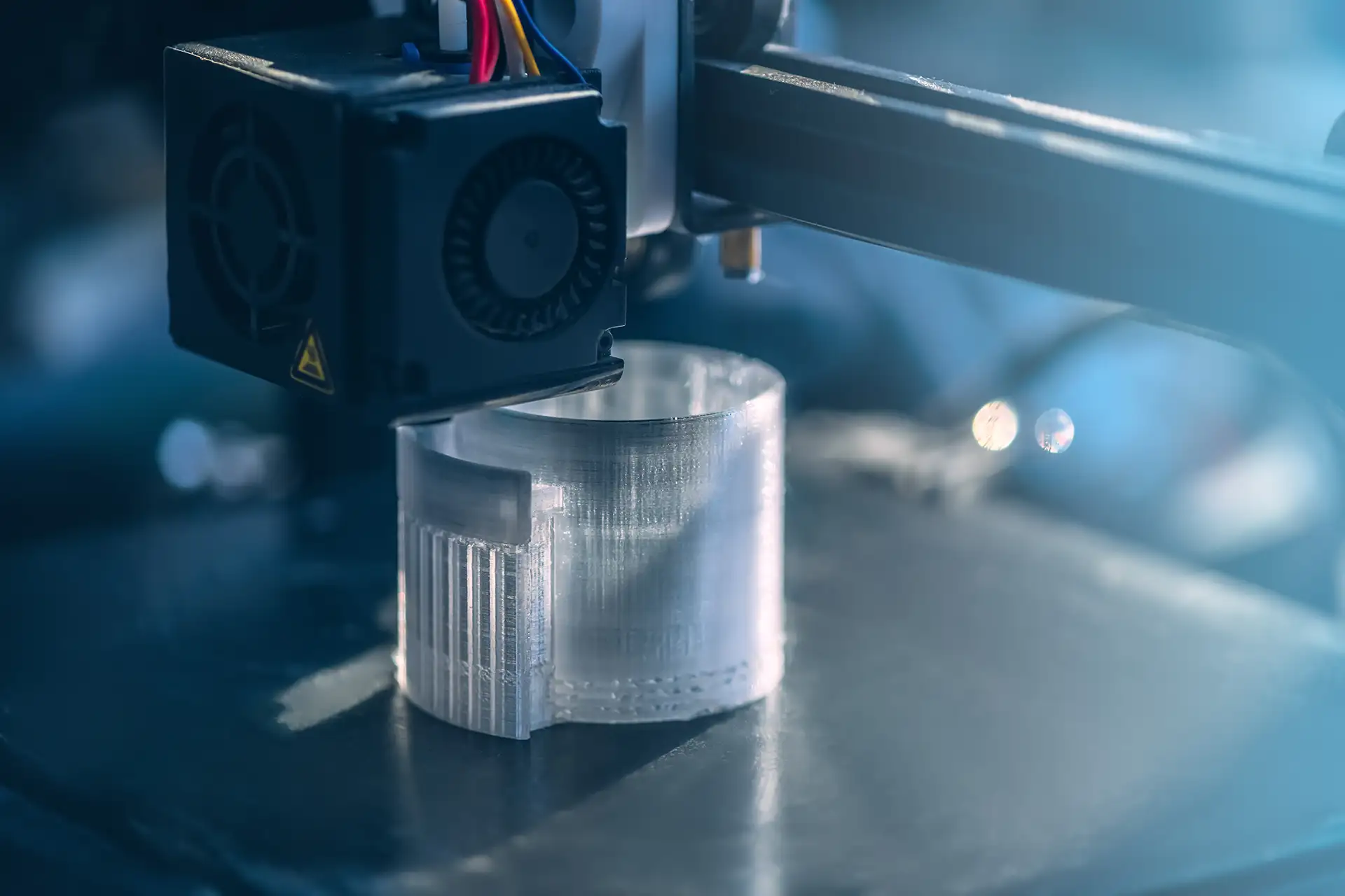 3D printer creating a round plastic object showing the FDM layer-by-layer printing process