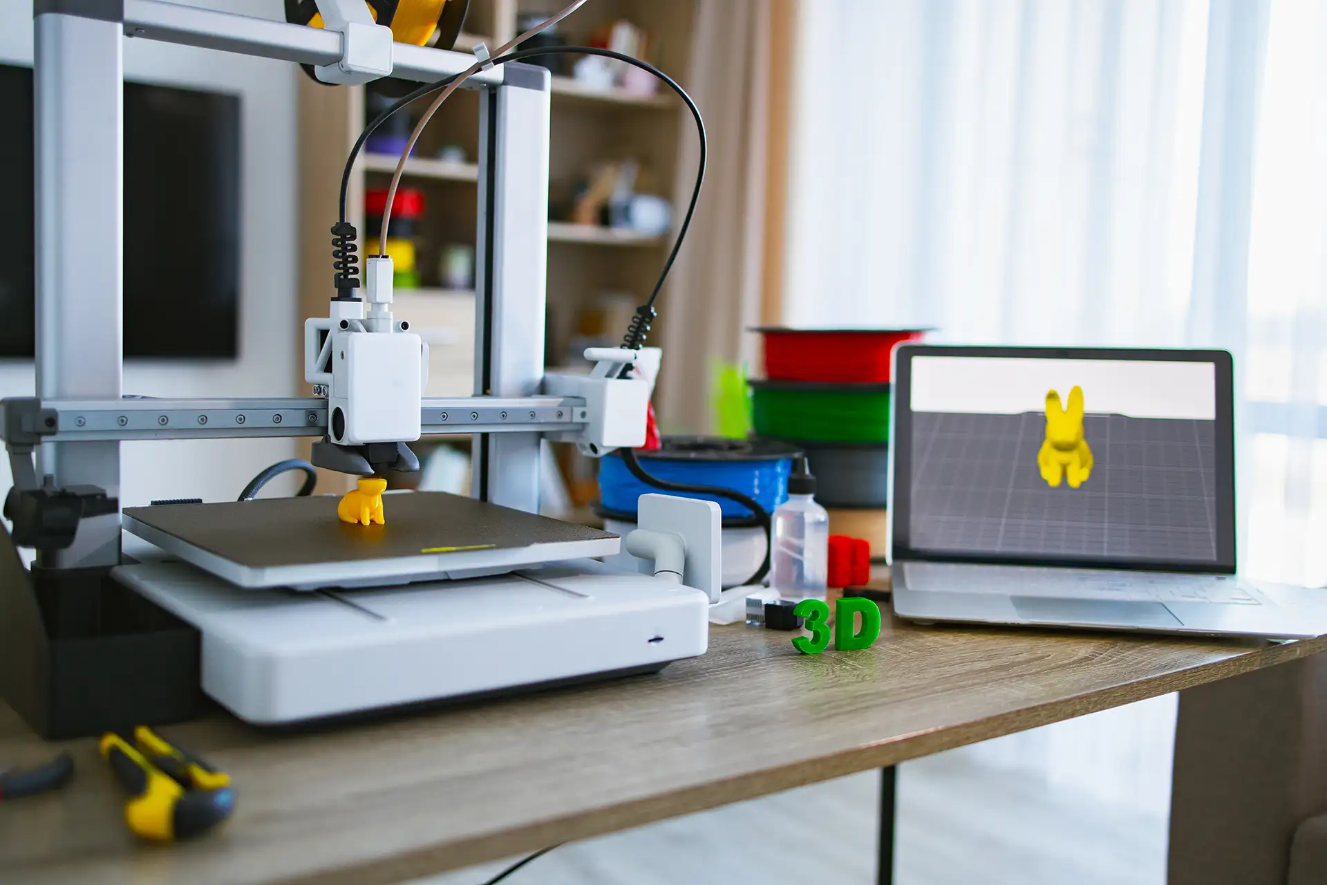 3D Printer With Design File on Laptop 3D printer creating an object with a laptop showing the 3D design file on screen