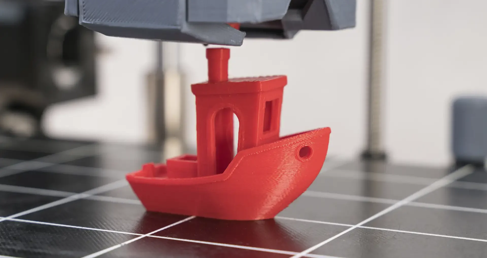 Red 3D Printed Boat Being Created on Print Bed Red 3D printed boat model being created on a printer bed showing the FDM printing process