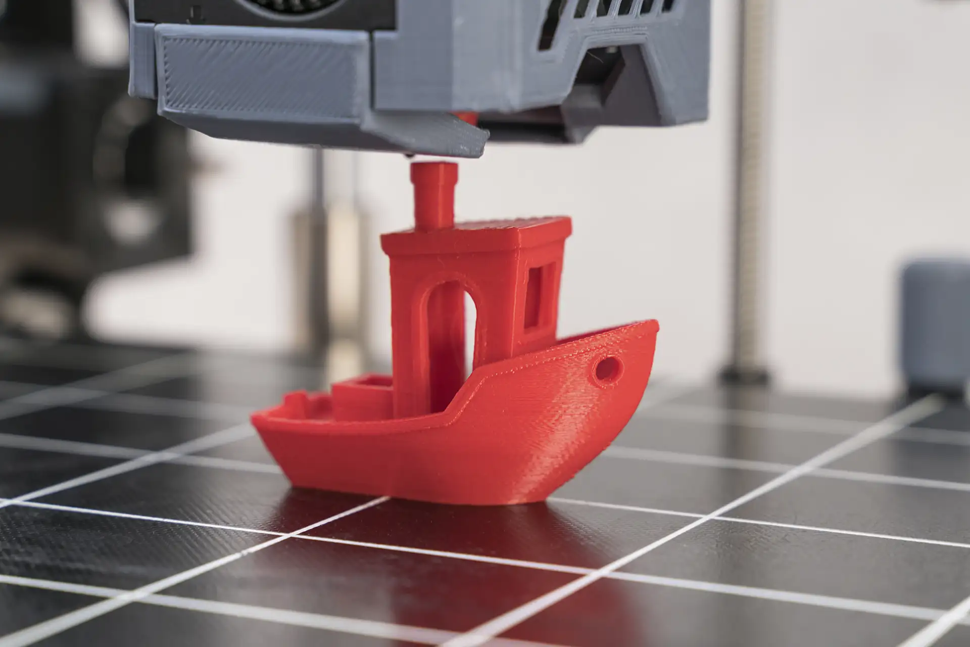 Red 3D Printed Boat Being Created on Print Bed Red 3D printed boat model being created on a printer bed showing the FDM printing process