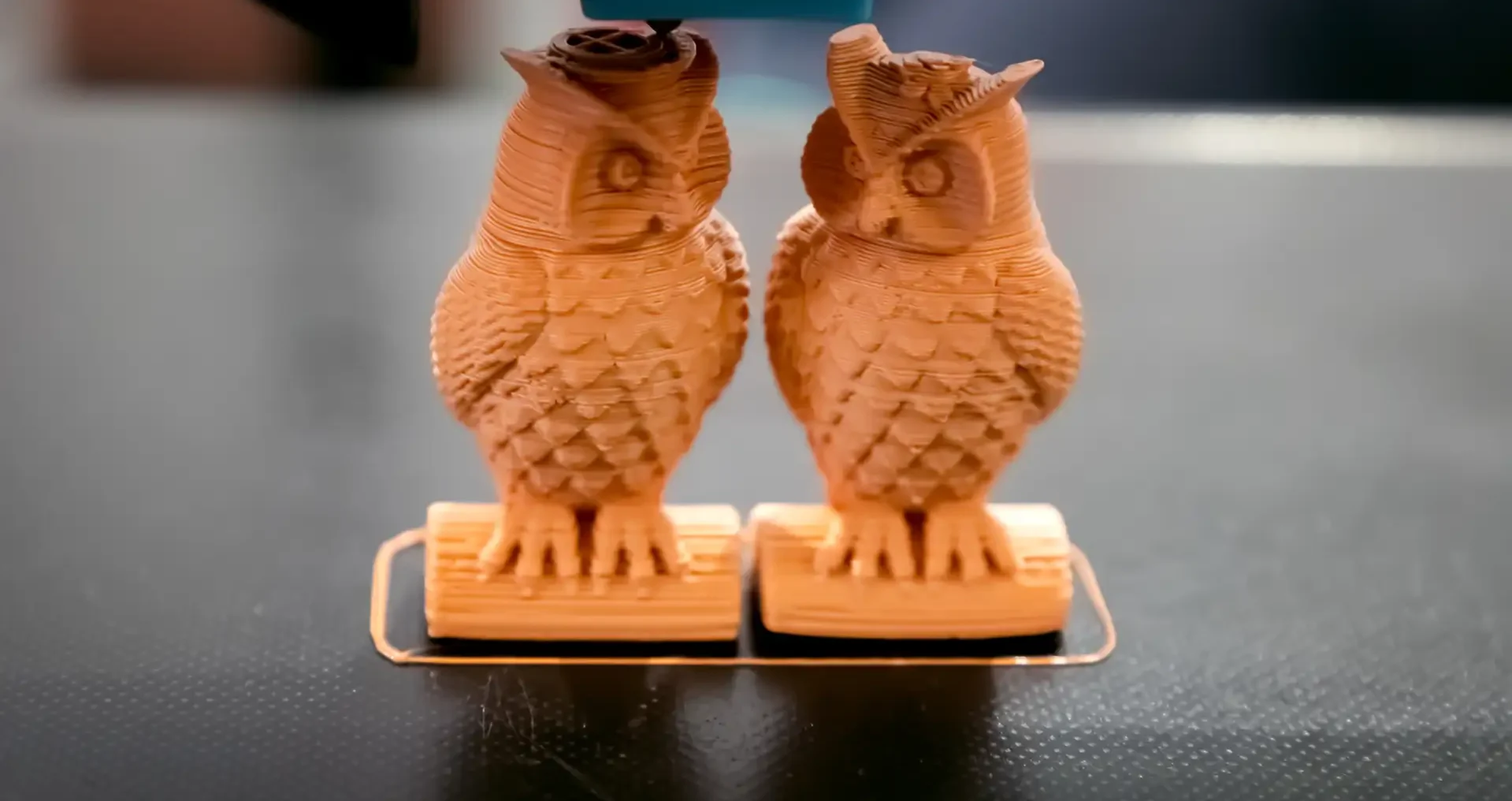 Two 3D printed owls in a workspace Two detailed 3D printed owl figurines sitting in a maker workspace