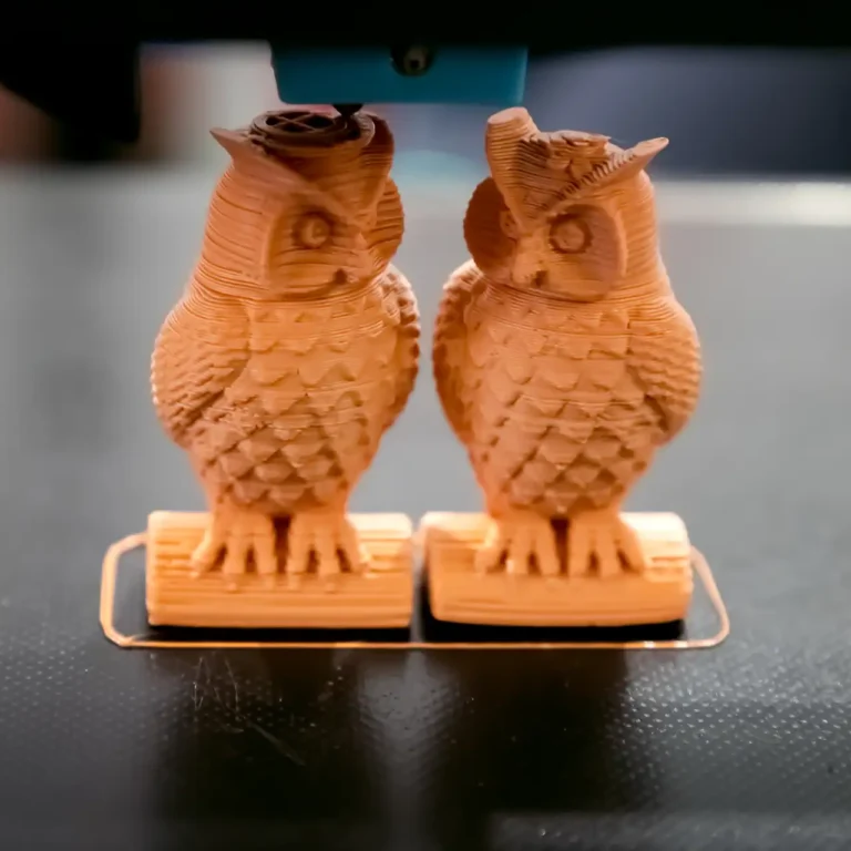 Two 3D printed owls in a workspace Two detailed 3D printed owl figurines sitting in a maker workspace