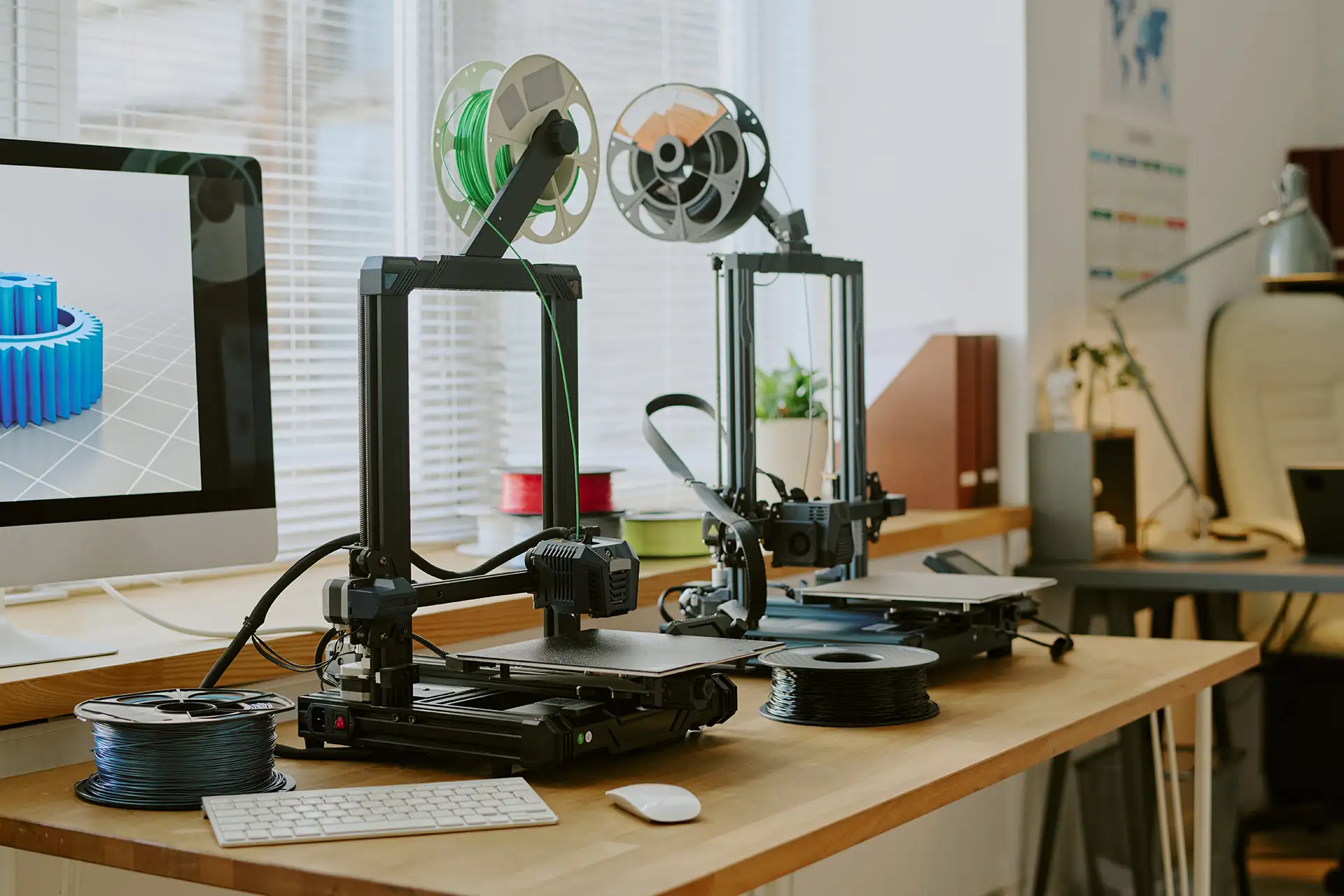 FDM 3D printing machines on office desk near computer Multiple FDM 3D printing machines running on an office desk next to a computer